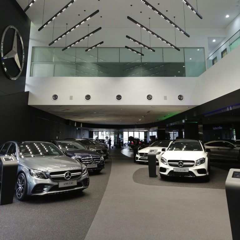Moderne Mercedes-Benz-Ausststellung mit mehreren Fahrzeugen in einem eleganten Showroom.